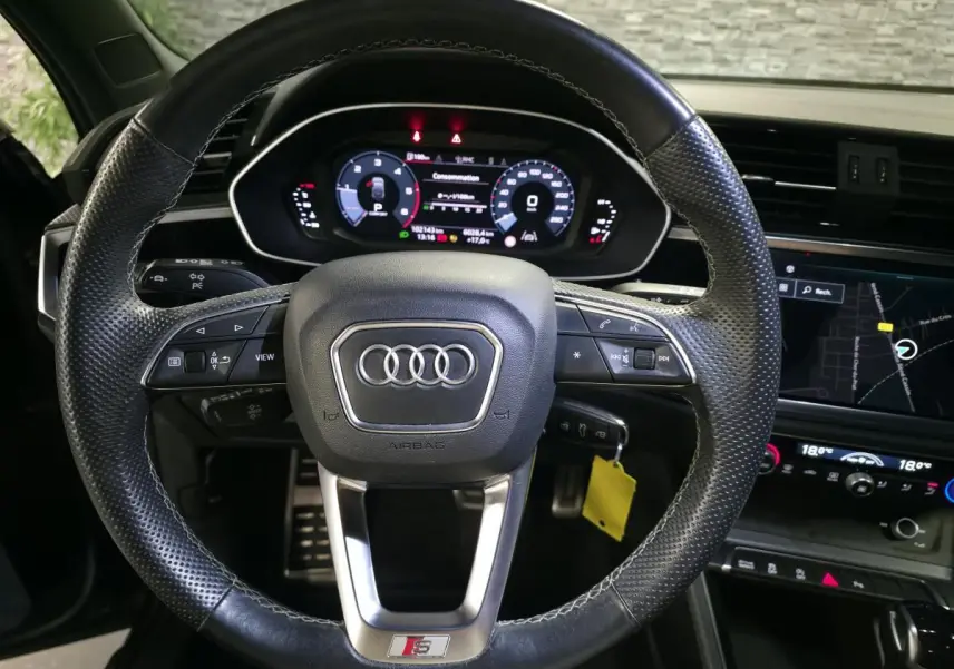 Vue rapprochée du volant cuir perforé noir avec logo S et tableau de bord numérique de l'Audi Q3 Sportback 2023.