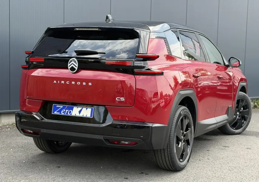 Vue 3/4 arrière droite du Citroën C5 Aircross 2026 rouge rubis avec toit noir et jantes alliage noires.