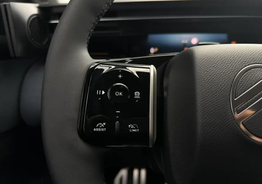 Gros plan sur les commandes noires au volant cuir noir du Citroën C5 Aircross hybride, avec logo argenté visible.