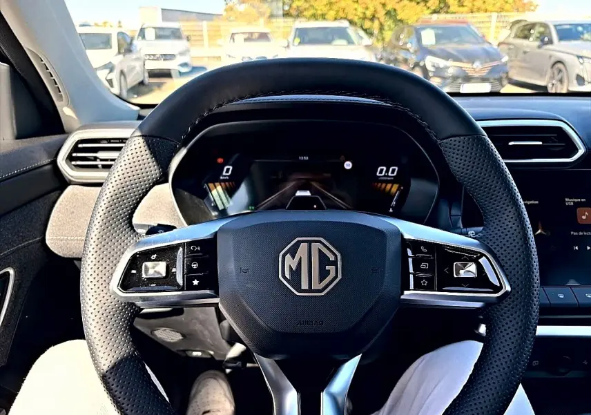 Vue intérieure centrée sur le volant perforé noir du MG ZS 1.5 hybrid 197 avec tableau de bord digital visible.