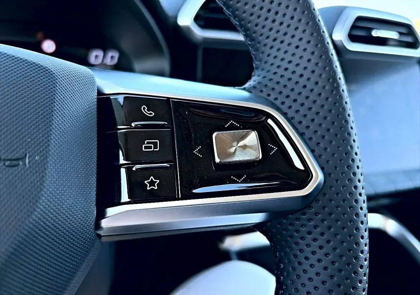 Gros plan sur les commandes multifonctions noires et argent du volant perforé du MG Motor ZS hybride noir.
