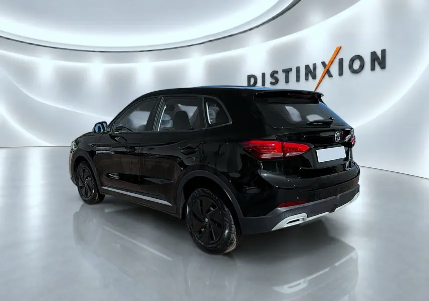 Vue 3/4 arrière droite d'un MG ZS noir brillant dans un showroom lumineux avec logo Distinxion en arrière-plan.
