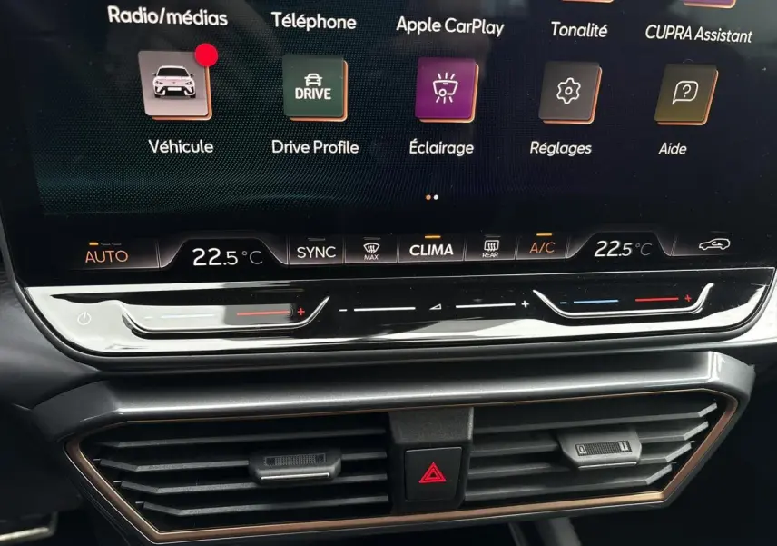 Détail de l'écran tactile central et commandes de climatisation du CUPRA LEON ST gris Graphene, intérieur moderne et épuré.