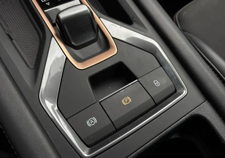 Gros plan sur la console centrale noire et grise du CUPRA LEON ST 2025 avec levier de vitesse et boutons de frein électrique.