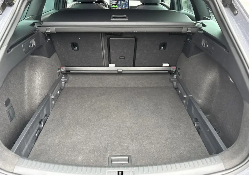 Coffre spacieux vu de l'arrière ouvert du CUPRA LEON ST gris Graphene avec banquette arrière et tablette arrière visible.