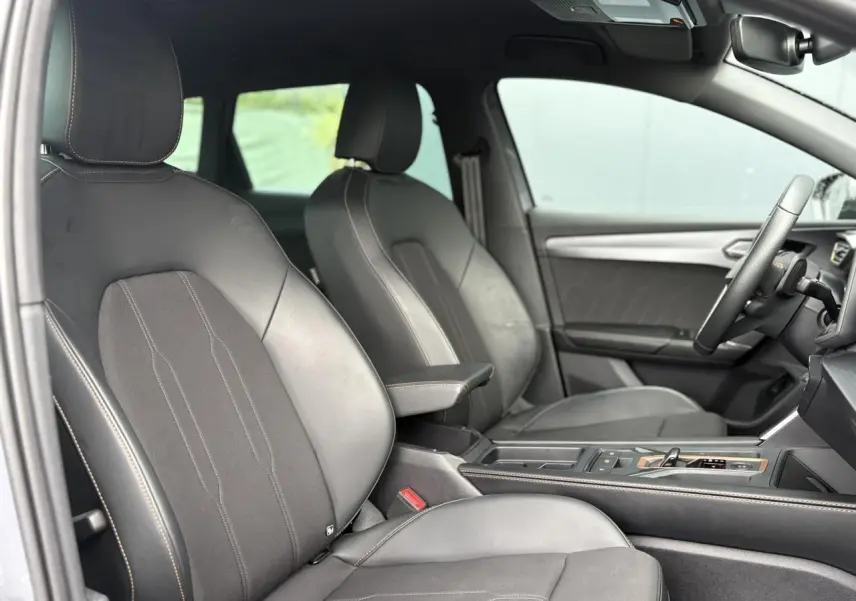 Intérieur de la CUPRA LEON ST 2025 vu côté gauche, sièges en cuir noir avec surpiqûres contrastées et console centrale moderne.