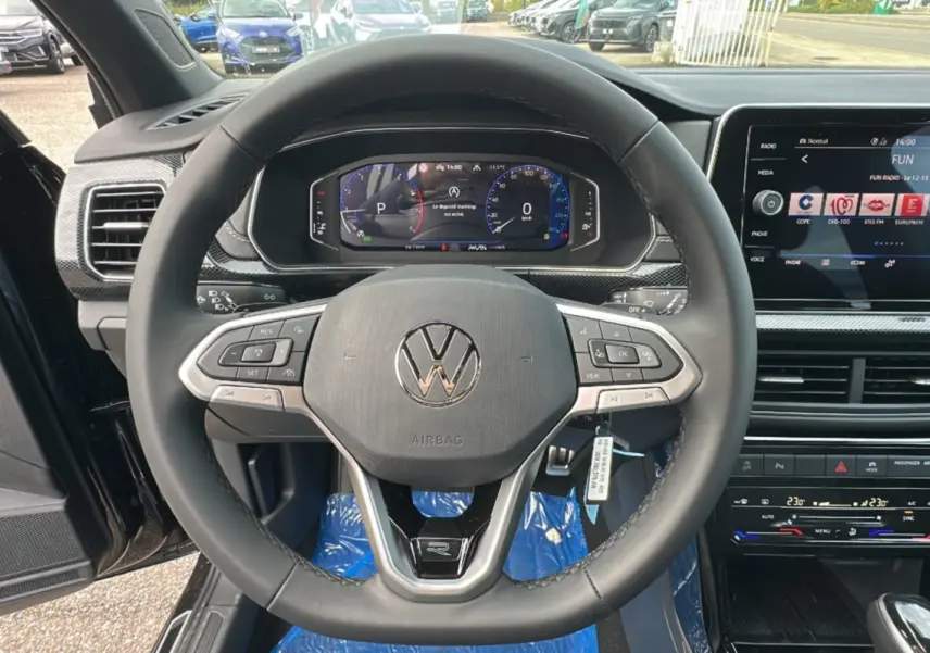 Vue intérieure centrée sur le volant cuir multifonctions et tableau de bord digital du Volkswagen T-Cross noir intense 2025.