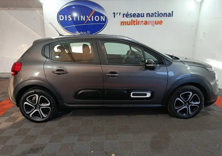 Vue latérale droite d'une Citroën C3 2024 gris foncé avec protections latérales noires et jantes bicolores.