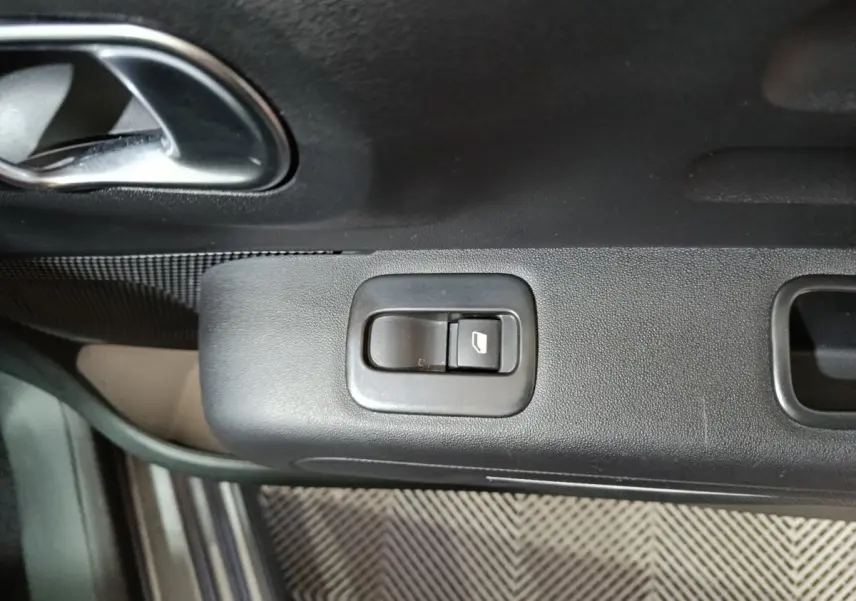 Gros plan sur le bouton de commande de la vitre électrique côté conducteur d’une Citroën C3 gris foncé, intérieur noir.