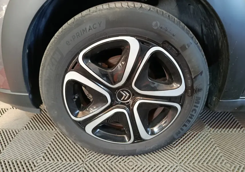 Gros plan sur la roue avant droite d’une Citroën C3 gris foncé, jante alliage noire et argent avec logo Citroën central.