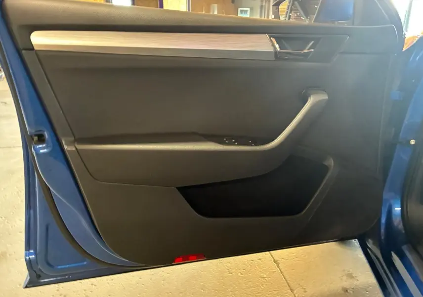 Intérieur de la porte avant gauche d'une Skoda Superb Combi bleu 2021, avec garniture noire et insert décoratif gris.