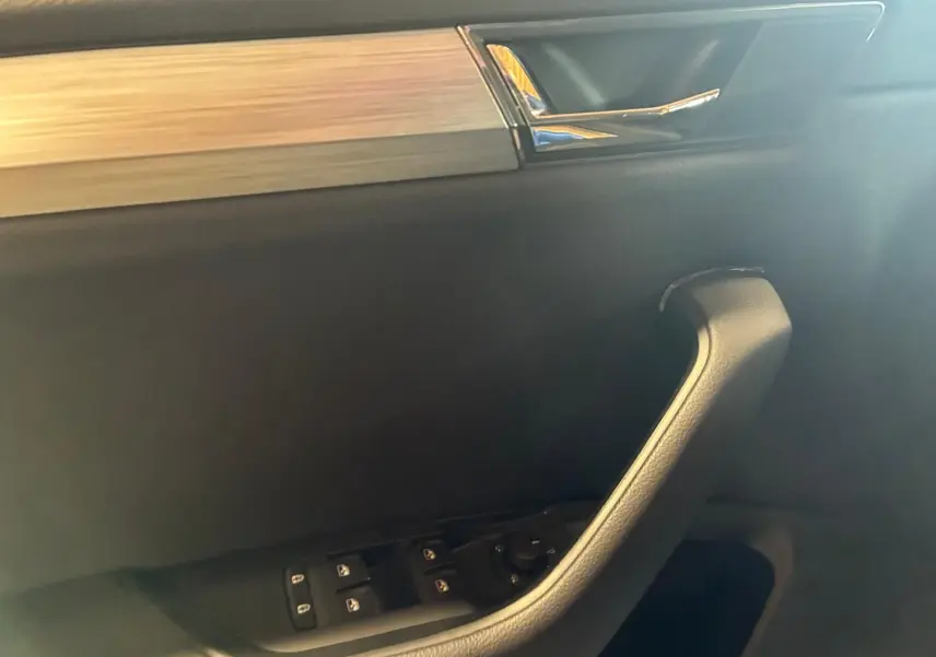 Poignée de porte intérieure côté conducteur de Skoda Superb Combi 2021, avec commande des vitres et insert décoratif chromé.