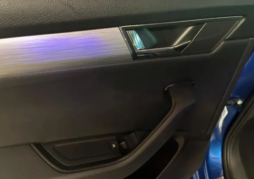 Détail de la porte intérieure côté gauche de la Skoda Superb Combi 2021 bleu, avec poignée noire et insert argenté.