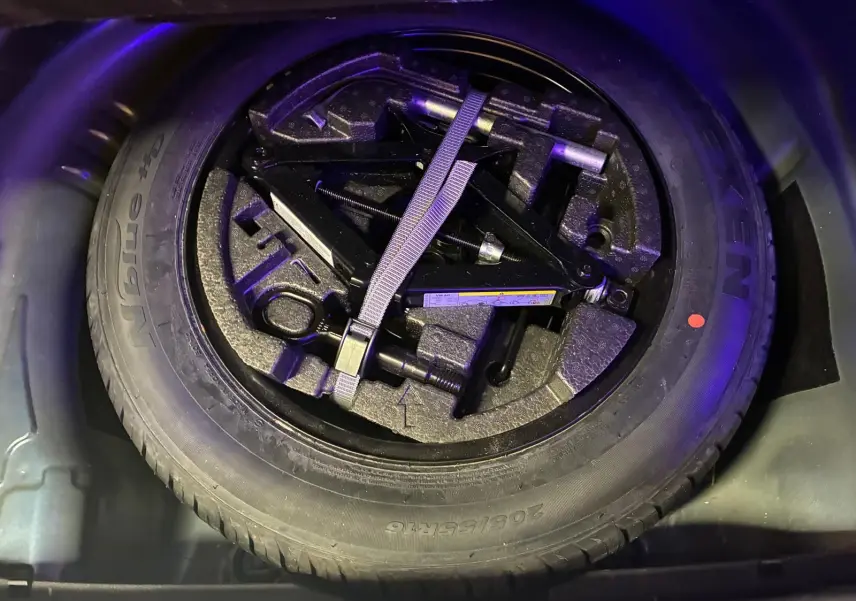 Roue de secours avec outils de changement dans le coffre d'une Skoda Superb Combi bleu 2021.