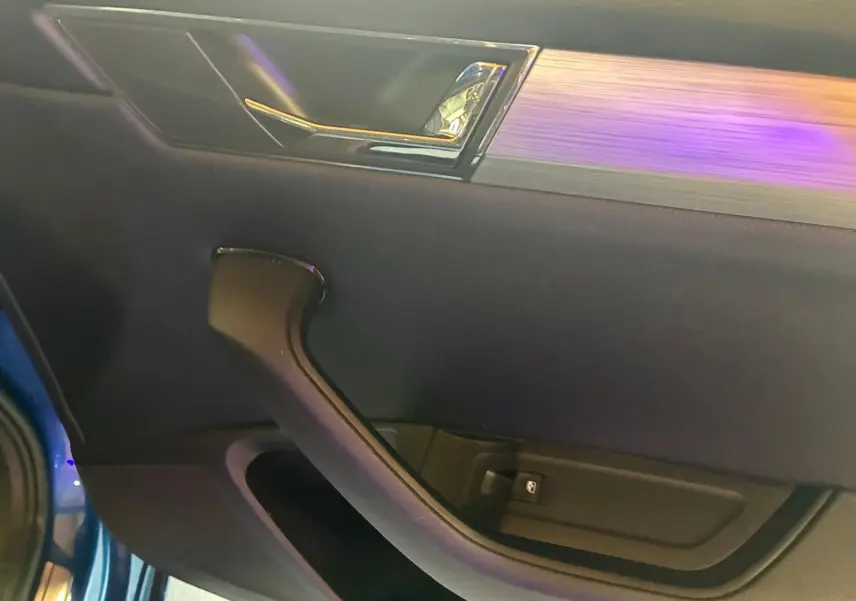 Gros plan sur la porte intérieure côté gauche d’une Skoda Superb Combi bleu, avec poignée noire et insert décoratif argenté.
