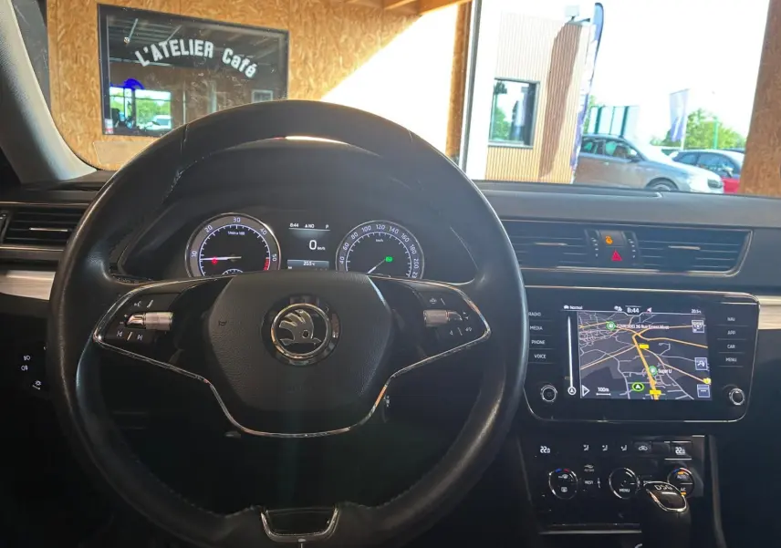 Vue intérieure centrée sur le volant noir et le tableau de bord avec écran GPS tactile de la Skoda Superb Combi 2021.