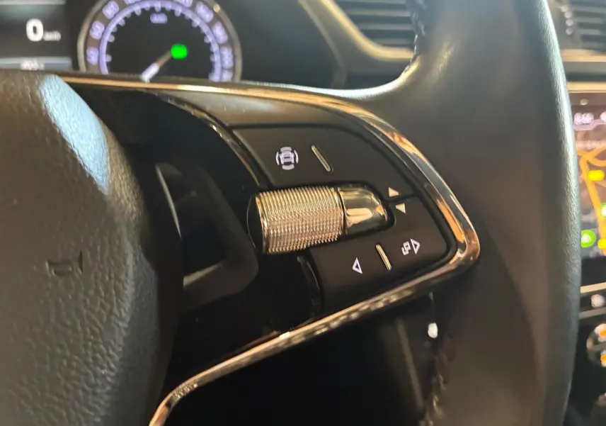 Gros plan sur les commandes à droite du volant noir d'une Skoda Superb Combi 2021, avec tableau de bord et écran en arrière-plan.