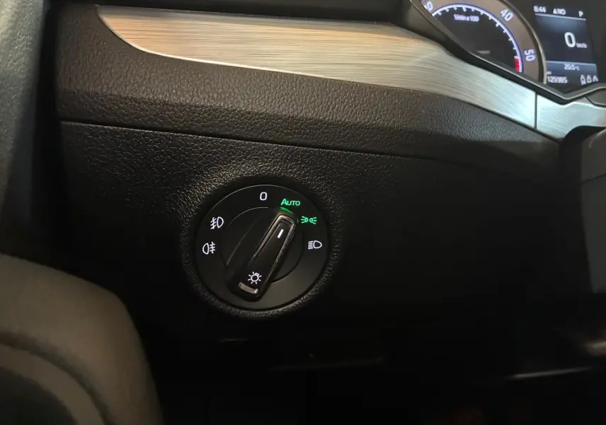 Gros plan sur le bouton de commande des phares avec tableau de bord partiel de la Skoda Superb Combi 2021 intérieur noir.