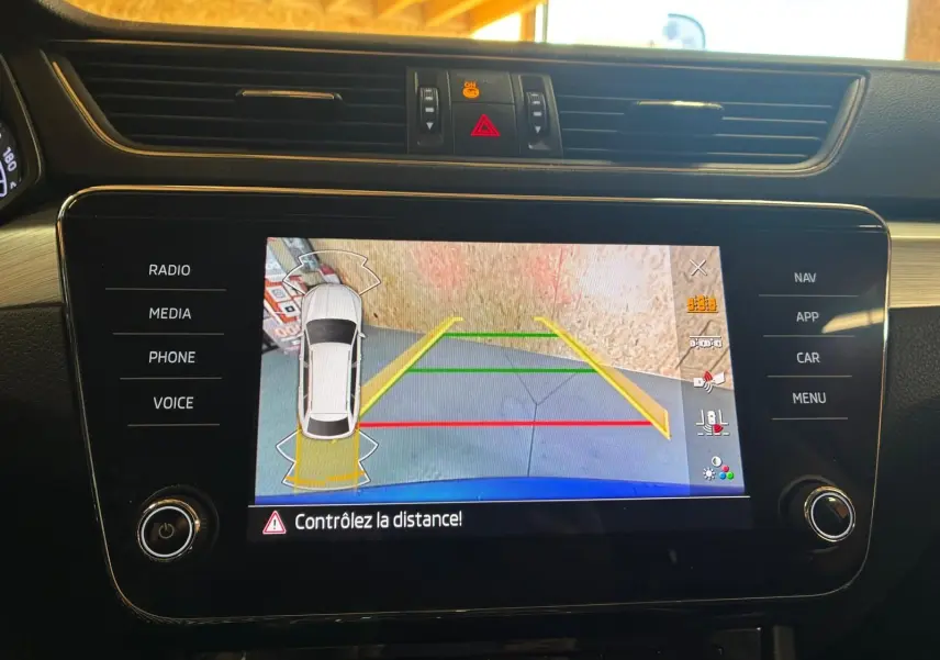 Écran central de la Skoda Superb Combi bleu 2021 montrant la caméra de recul avec guidage de trajectoire coloré.