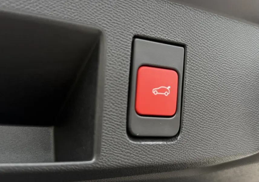 Bouton rouge de hayon électrique sur panneau intérieur noir texturé du Citroën C5 Aircross blanc et noir.