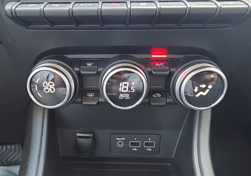 Gros plan sur les commandes de climatisation automatique du Renault Captur noir, avec affichage digital à 18,5°C.