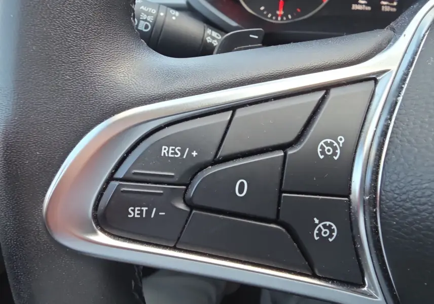 Gros plan sur les commandes du régulateur de vitesse au volant noir du Renault Captur 2021.