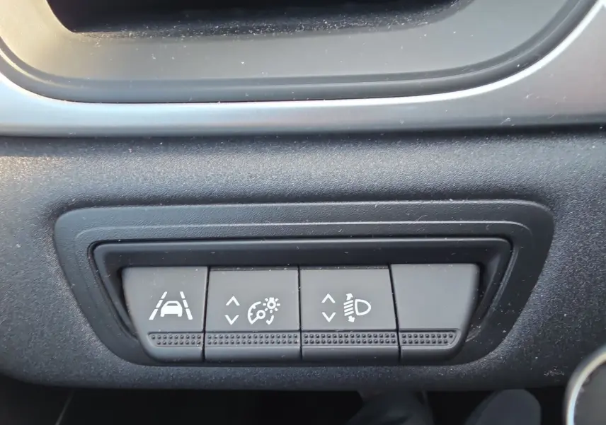 Gros plan sur les commandes noires du tableau de bord du Renault Captur 2021, boutons d’aide à la conduite visibles.