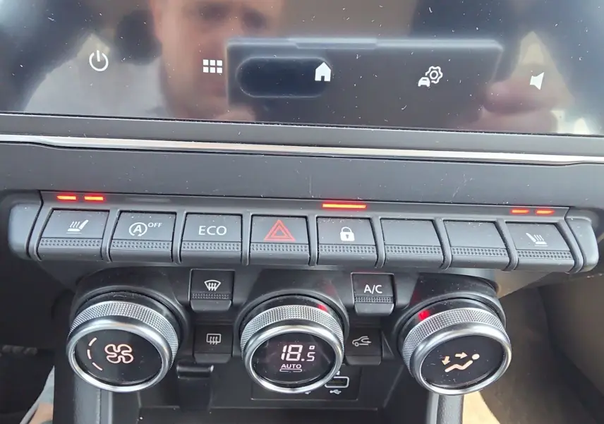 Vue rapprochée de la console centrale du Renault Captur noir, montrant les commandes de climatisation et sièges chauffants activés.