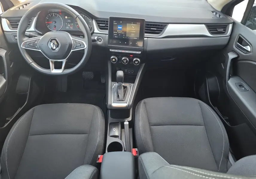 Vue intérieure avant du Renault Captur noir 2021, montrant le tableau de bord, volant multifonction et console centrale avec écran tactile.