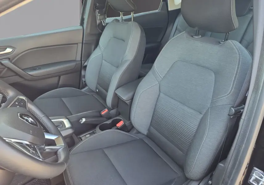 Vue intérieure rapprochée des sièges avant gris du Renault Captur noir, avec volant et accoudoir visibles côté gauche.