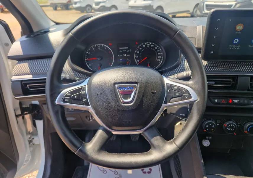 Vue frontale du volant noir de la Dacia Sandero 2022 avec tableau de bord et écran tactile visible.
