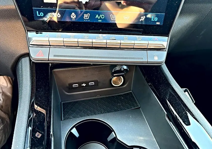 Gros plan sur la console centrale noire du Renault Austral 1.2 e-tech, montrant ports USB-C et prise 12V sous l'écran tactile.