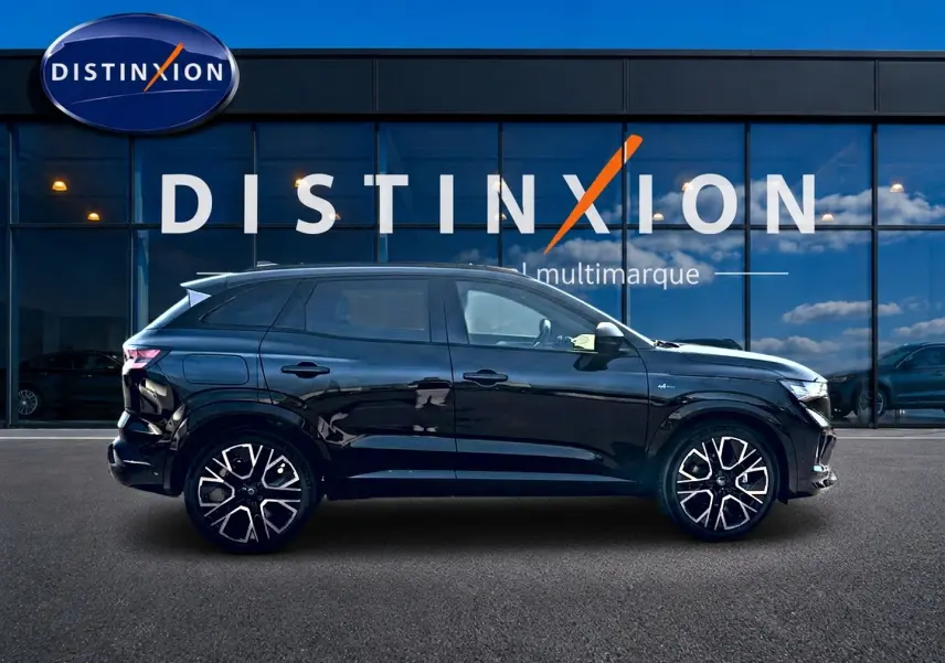 Profil latéral gauche d’un Renault Austral noir brillant avec jantes alu et toit surélevé devant une vitrine Distinxion.