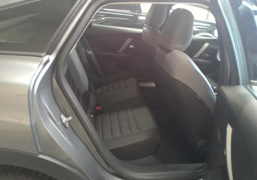 Vue intérieure côté arrière droit de la Citroën C4 hybride gris Mercury, montrant les sièges arrière en tissu noir.