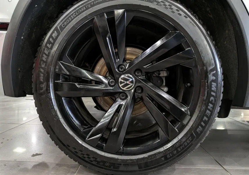 Gros plan sur la roue avant droite du Volkswagen Tiguan 2024, jante noire brillante et pneu Michelin CrossClimate.