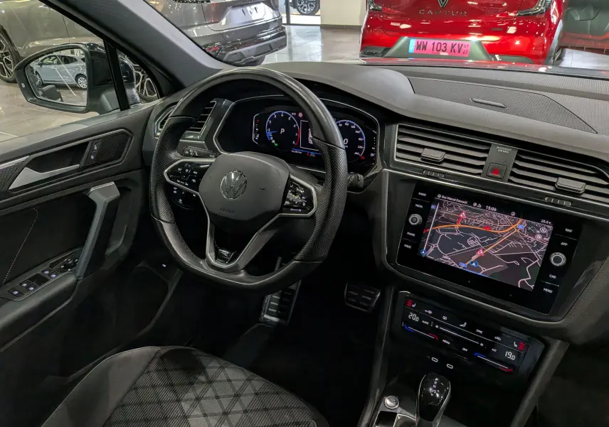Vue intérieure côté conducteur du Volkswagen Tiguan 2024, tableau de bord noir avec écran tactile et volant multifonction.