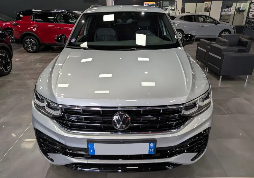 Vue avant d’un Volkswagen Tiguan 1.5 TSI R-Line 2024 en reflet d’argent, avec calandre noire et logo VW central.