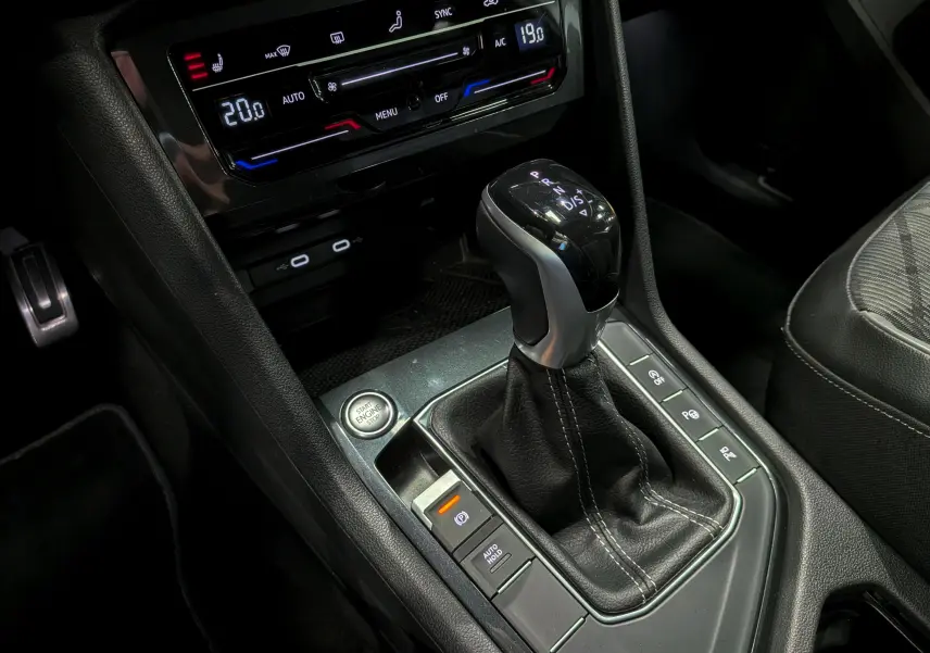 Gros plan sur la console centrale du Volkswagen Tiguan 2024, mettant en valeur le levier de vitesse DSG et la climatisation digitale.