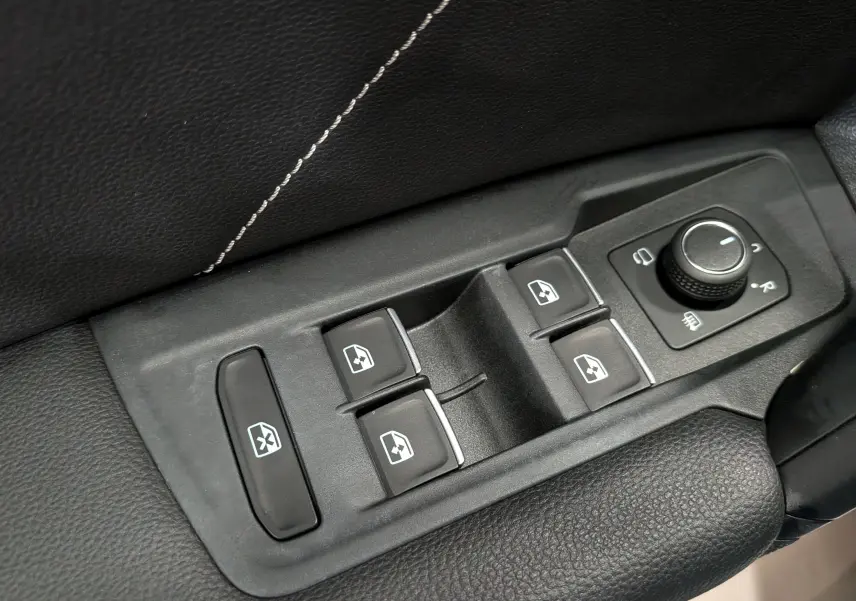 Gros plan sur les commandes de lève-vitres et réglage des rétroviseurs du Volkswagen Tiguan 2024 finition R-Line.