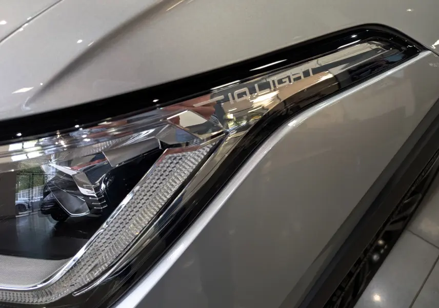 Gros plan sur le phare avant droit du Volkswagen Tiguan 2024 reflet d'argent avec signature lumineuse IQ.LIGHT.