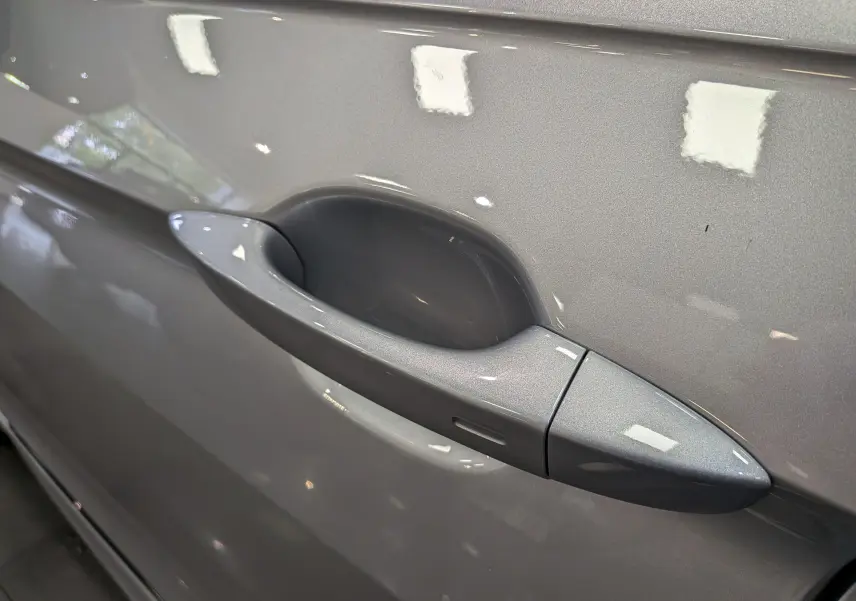Poignée de porte côté gauche en gros plan sur Volkswagen Tiguan 2024 reflet d'argent avec finition lisse et capteur intégré.