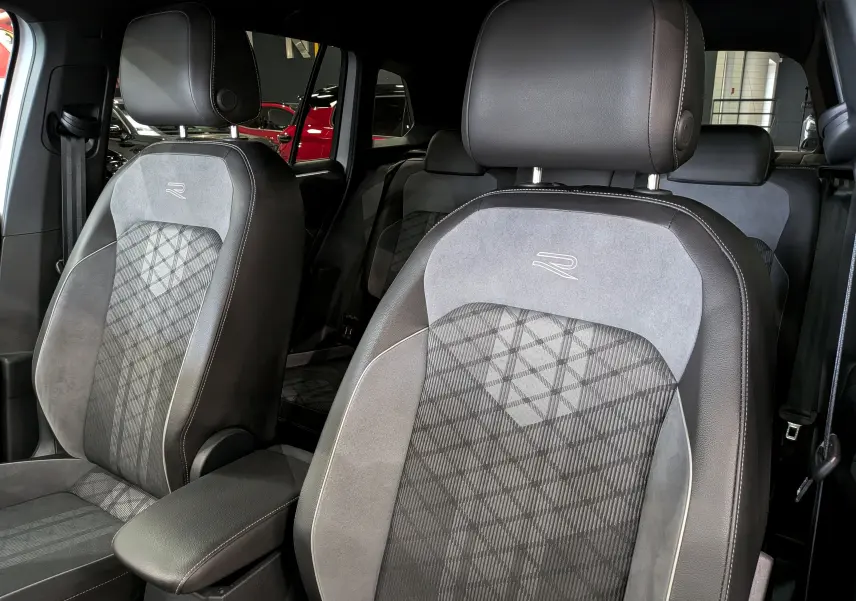 Gros plan sur les sièges avant en cuir gris et alcantara avec logo R du Volkswagen Tiguan 2024, ambiance intérieure raffinée.