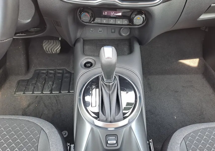 Vue rapprochée de la console centrale du Nissan Juke Hybrid 2025, avec levier de boîte auto et commandes climatisation.