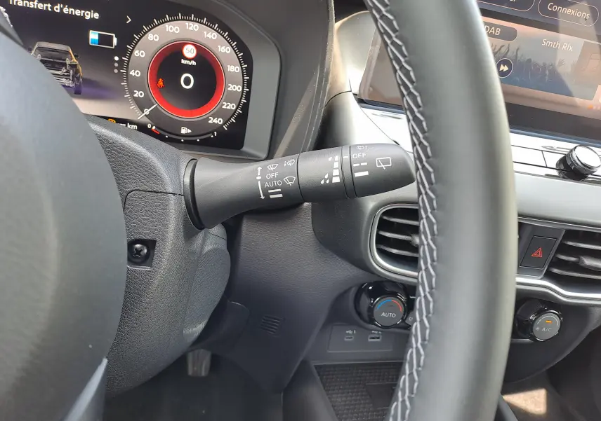 Vue rapprochée du tableau de bord côté gauche du Nissan Juke Hybrid 2025, montrant le volant et commandes d'essuie-glace.