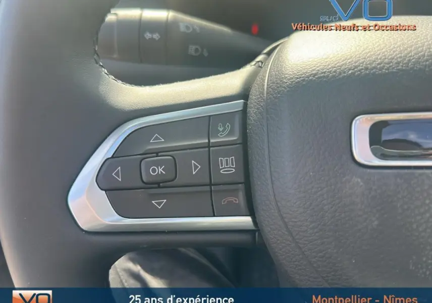 Gros plan sur les commandes gauche du volant cuir du Jeep Compass noir 2023, avec boutons de navigation et appel.