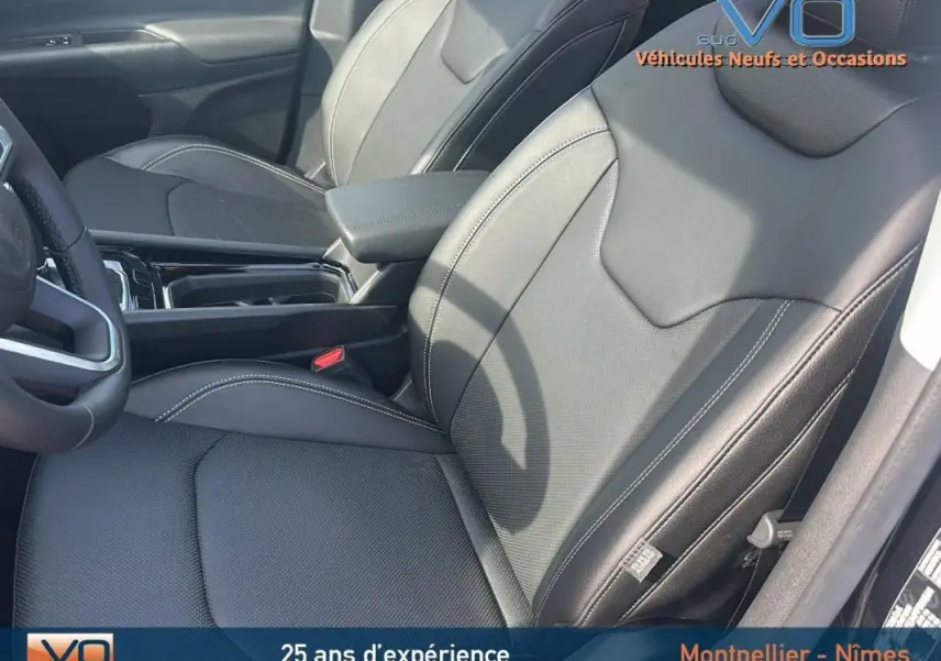 Intérieur noir du Jeep Compass 2023, vue côté conducteur sur sièges cuir avec accoudoir central et volant partiel visible.