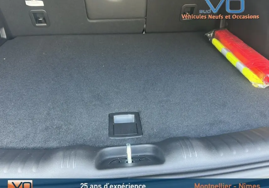 Coffre spacieux et propre du Jeep Compass noir 2023, avec tapis de sol et triangle de signalisation visible à droite.