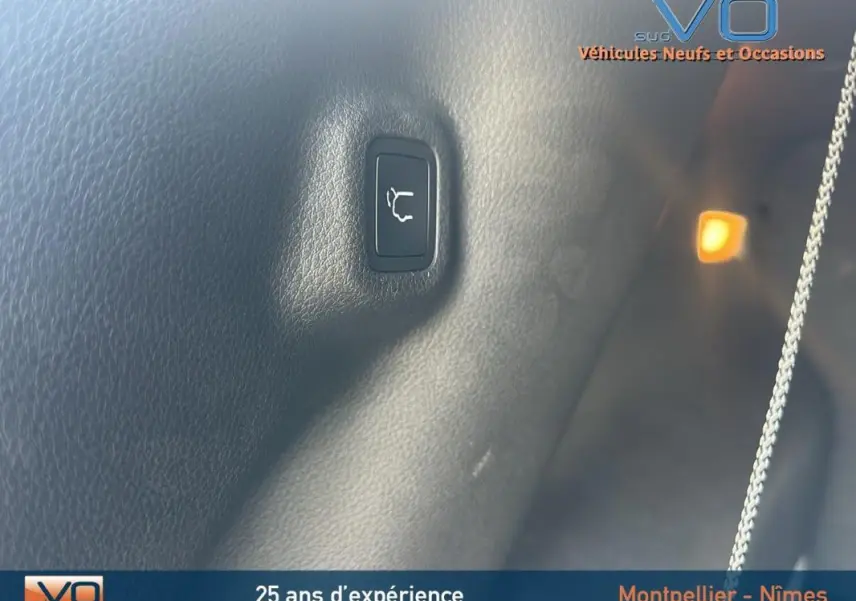 Gros plan sur le bouton d'ouverture du coffre dans l'habitacle noir du Jeep Compass 2023 e-Hybrid.