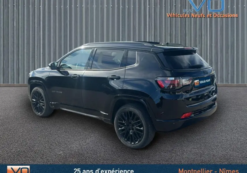 Vue 3/4 arrière droite d'un Jeep Compass noir 2023 avec jantes alliage noires et barres de toit visibles.