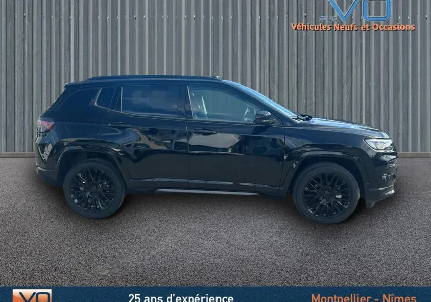 Profil côté gauche du Jeep Compass noir 2023 avec jantes alliage noires et barres de toit visibles.